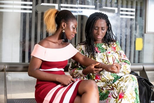 two young women sitting in a waiting room watching watch looking impatient.