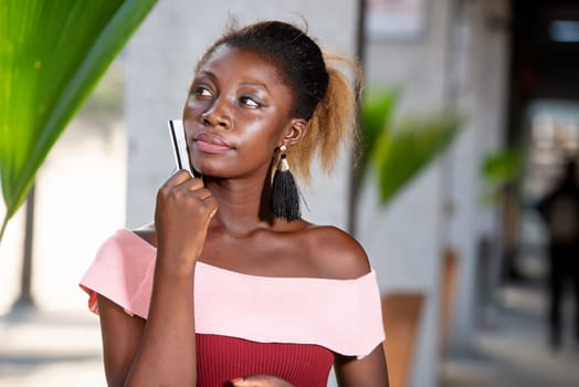 Portrait of young attractive woman holding shopping bags and a credit card, reflecting on her expenses to make in shop. concept of urban lifestyle concept in the background.