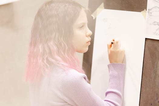 Girl 11 years old craftswoman are painting on canvas in studio standing in front of easel. Portrait of a girl painting during an art class