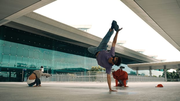 Group of diverse hipster or street dancer doing head spin in front of mall. Happy energetic break dancer practice b-boy step dancing with friends. Outdoor sport 2024. Street dancer concept. Sprightly.