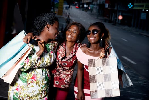 group of young women standing outdoors laughing while holding shopping bags.