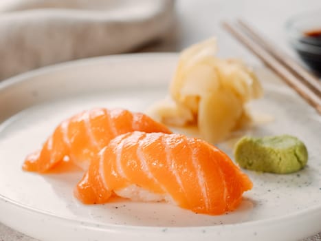 Two salmon sushi nigiri on white plate. Fresh Japanese sushi salmon served wasabi in Japanese restaurant. Japanese food such as salmon sushi and sashimi concept. Salmon sushi, Japanese food concept