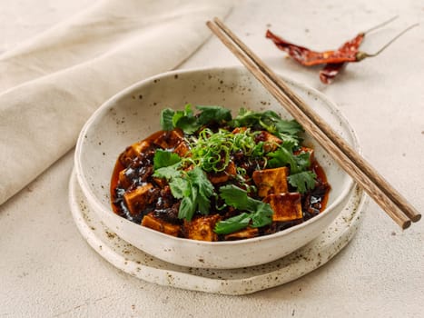 Spicy asian tofu salad or appetizer. Fried tofu decorated green onion - chinese dish with sauce. Serving Asian dish in restaurant in plate. Copy space