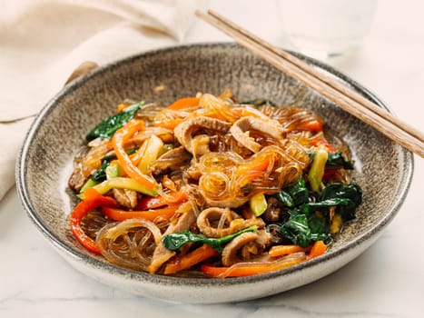 Asian noodles with meat and vegetables. Stir fry noodles with vegetables and beef, pork or chicken. Plate of asian buckwheat soba noodles with vegetables and chicken.