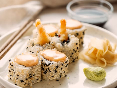 Tempura shrimp sushi roll - japanese food style on white plate over serving table. Shrimp tempura roll maki sushi