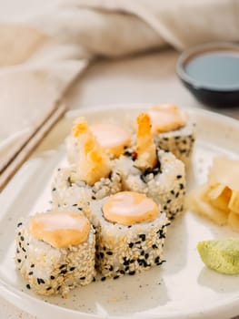 Tempura shrimp sushi roll - japanese food style on white plate over serving table. Shrimp tempura roll maki sushi