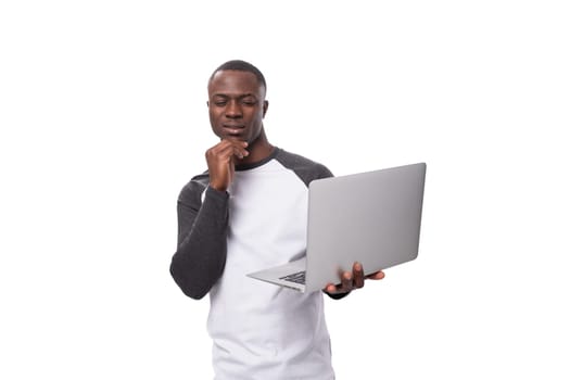a young American guy dressed in a long-sleeve sweater owns a portable laptop for remote work.