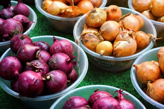 London, United Kingdom - February 04, 2019: Yellow and purple onions on display at typical food market at Lewisham, vegetables and fruit is usually sold in bowls, with same price tag