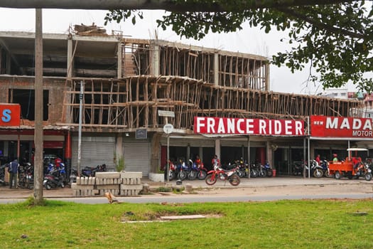 Antananarivo, Madagascar - April 24, 2019: Wooden scaffolding on building where another floor is being built above bike shop. Madagascar is poor, people can't afford to use expensive steel tubes.