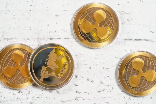 Top down view, golden XRP ripple cryptocurrency coins on white stone board