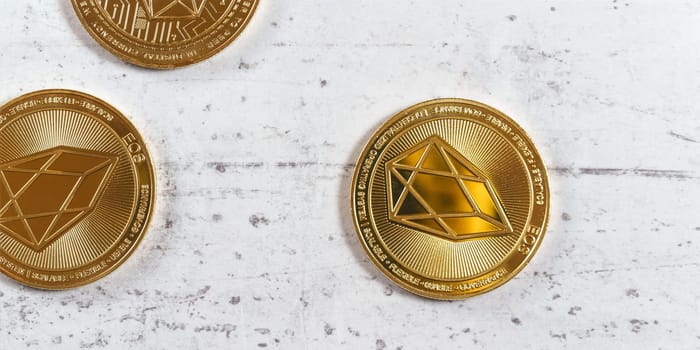 Top down view, golden commemorative EOS - EOSIO  cryptocurrency - coins on white stone board