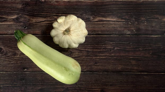 Top down view, pattypan squash and zucchini on dark wooden board, wide banner, space for text right side