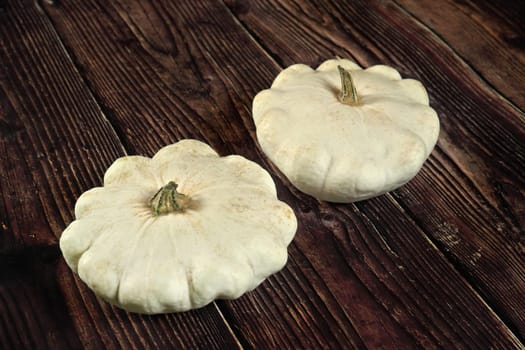 Two white pattypan squash heads on dark wooden board