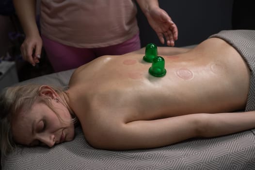 A woman undergoing a massage using vacuum plastic jars