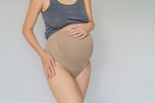 Pregnant bliss: Mom-to-be embraces her baby bump with a soft fabric bandage, providing gentle support. Maternity made comfortable.