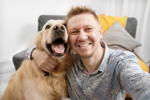 Portrait of Smiling man taking selfie with his cute golden retriever dog