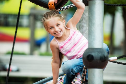 Happy smiling little girl playing at the playground outdoor