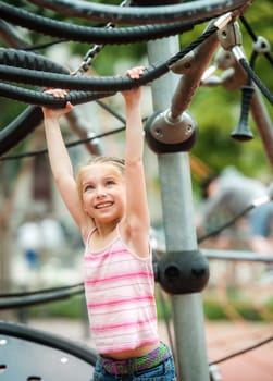 Happy cute smiling little girl playing at the playground outdoor