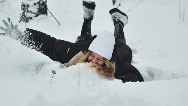 A girl falls on the snow in winter in the forest