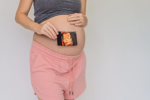 Expectant mother tenderly connects with her unborn child, holding ultrasound photo to her pregnant belly.