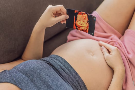 Expectant mother tenderly connects with her unborn child, holding ultrasound photo to her pregnant belly.