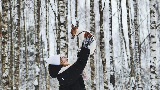 A girl drops off her Jack Russell Terrier dog in the woods in winter