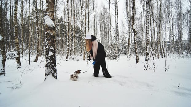 A girl and her Jack Russell Terrier dog are running through the woods