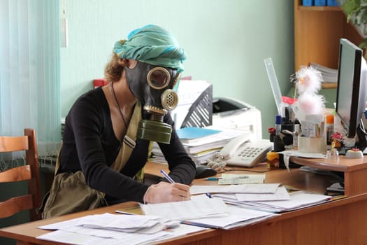 A girl wearing a gas mask sits at a desk and fills out paperwork in the office Nuclear threat