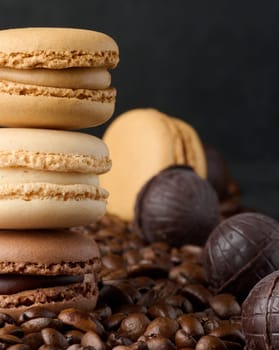 Stack of multi-colored macarons on a background of coffee beans, black background
