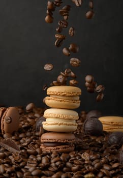 Stack of colorful macarons and flying coffee beans on a black background