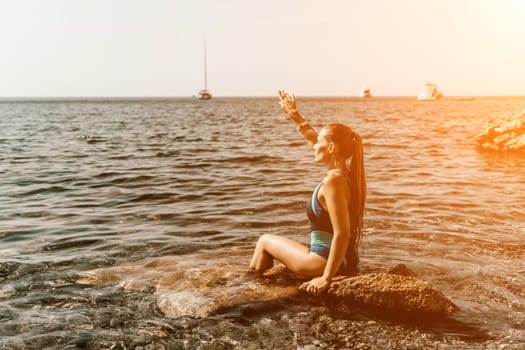 Woman travel summer sea. A happy tourist in a blue bikini enjoying the scenic view of the sea and volcanic mountains while taking pictures to capture the memories of her travel adventure