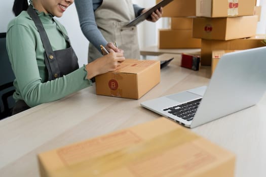 Asian woman write parcel box to prepare for delivery to customer. e-business concept.