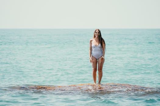 Woman sea yoga. Back view of free calm happy satisfied woman with long hair standing on top rock with yoga position against of sky by the sea. Healthy lifestyle outdoors in nature, fitness concept.