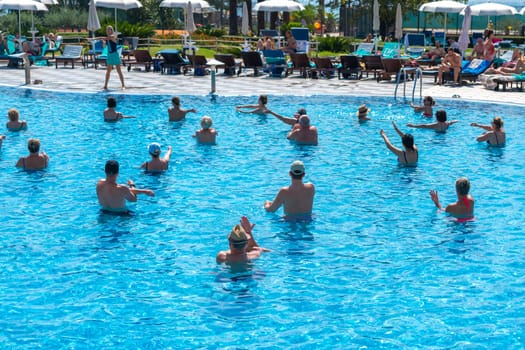 BUDVA, MONTENEGRO - SEPTEMBER 08, 2023: Group engaged in aqua aerobics at a hotel's outdoor pool. Concept of fitness and fun in water