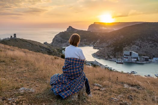 Happy woman on sunset in mountains. Woman siting with her back on the sunset in nature in summer. Silhouette