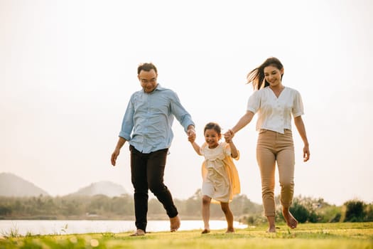 Asian parent and child walking and playing in a beautiful park, feeling the happiness and the cheerfulness of the season of spring, Happy family day