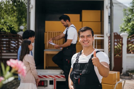 In a portrait a joyful mover unloads boxes from a truck into a new home. These movers display teamwork ensuring efficient relocation and spreading happiness. Moving day concept
