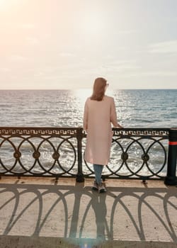 Woman travel sea. Young Happy woman in a long red dress posing on a beach near the sea on background of volcanic rocks, like in Iceland, sharing travel adventure journey