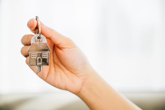 A woman holds house key symbolizing achievement in homeownership. Agent showcases model home signifying real estate success. Confidence and happiness radiate.