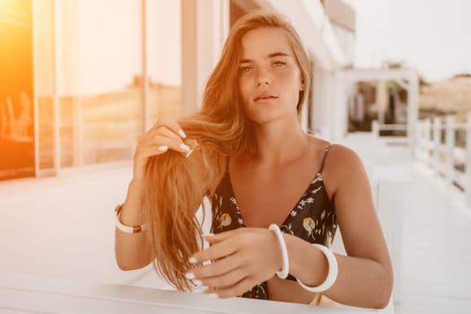 Happy woman portrait in cafe. Boho chic fashion style. Outdoor photo of young happy woman with long hair, sunny weather outdoors sitting in modern cafe