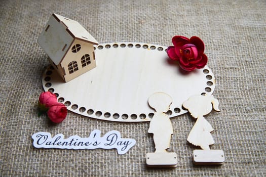 Wooden figurines of a couple, a house and the inscription Valentine's Day. The concept of a holiday of love and lovers. Background, texture, place for text and copy space