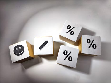 Wooden cubes in a column and row with white signs with a smiley sign, an arrow, a percentage. The concept of positivism. Positive thinking leads to the achievement of results and profits