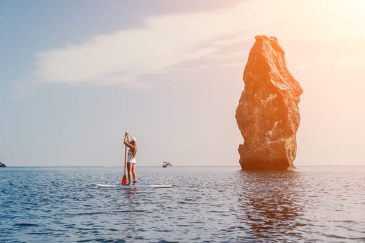 Close up shot of beautiful young caucasian woman with black hair and freckles looking at camera and smiling. Cute woman portrait in a pink bikini posing on a volcanic rock high above the sea