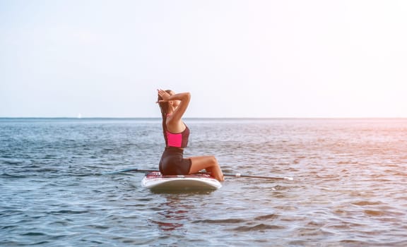 Silhouette of woman standing, surfing on SUP board, confident paddling through water surface. Idyllic sunset or sunrise. Sports active lifestyle at sea or river.