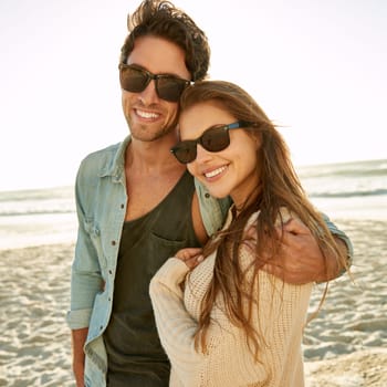 Couple, sea and sunglasses with embrace, happy or care for fashion, eye protection or vacation in summer. Man, woman and hug with glasses at beach for sun, smile and love by ocean on tropical holiday.