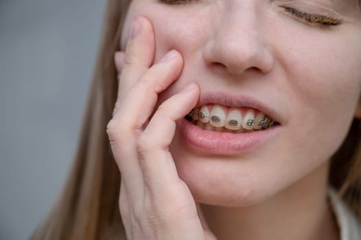 Close-up portrait of a red-haired girl suffering from pain due to braces. Young woman corrects bite with orthodontic appliance