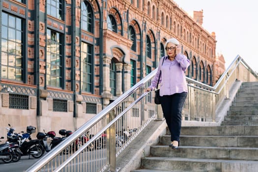 senior woman walking down stairs in the city, concept of elderly people leisure and active lifestyle
