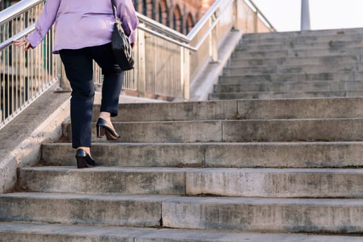 legs of unrecognizable senior woman walking up stairs, concept of elderly people leisure and active lifestyle, copy space for text