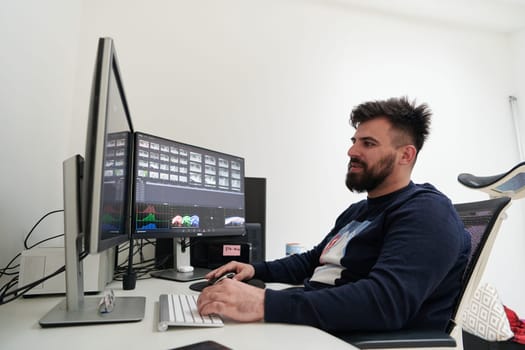 professional video editor enhancing digital footage using specialized software. Expert videographer in home office workspace editing on dual screen workstation computer desktop workplace