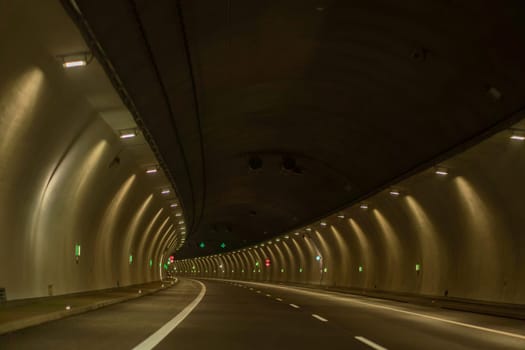 Underground city road tunnel, curve night illuminated freeway with car